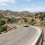 Rural Spanish road with a bend and warning signs indicating reduced speed.